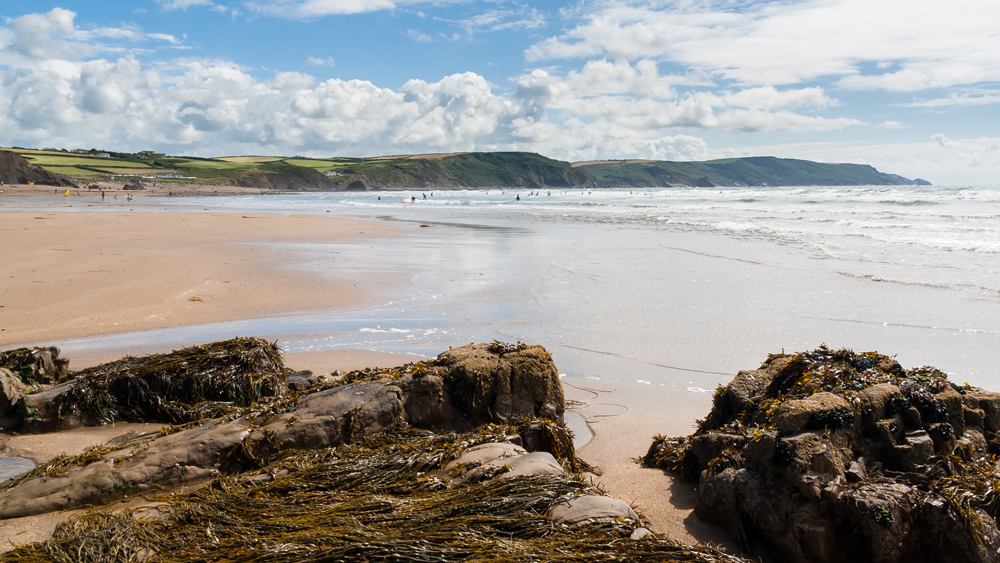 A family walking along the cliffs at Sandymouth Beach in Cornwall