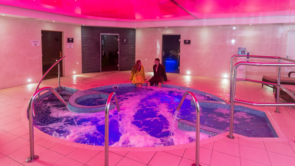 Couple sitting on the edge of the hydrotherapy pool at Brynteg Holiday Park.