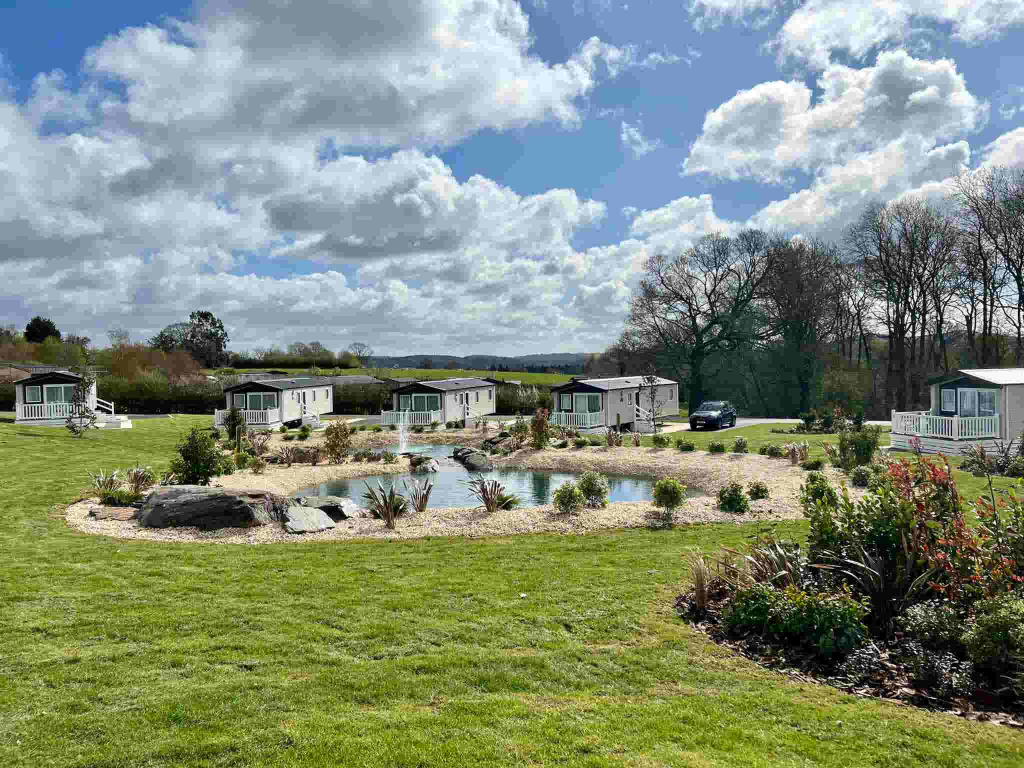 Holiday homes looking over a water feature on the Deer View holiday home development at Malvern View Country & Leisure Park