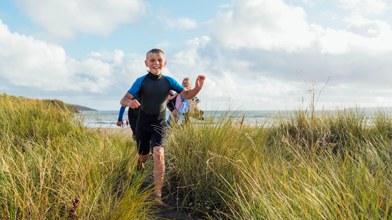 A family running through the sand dunes on a beach