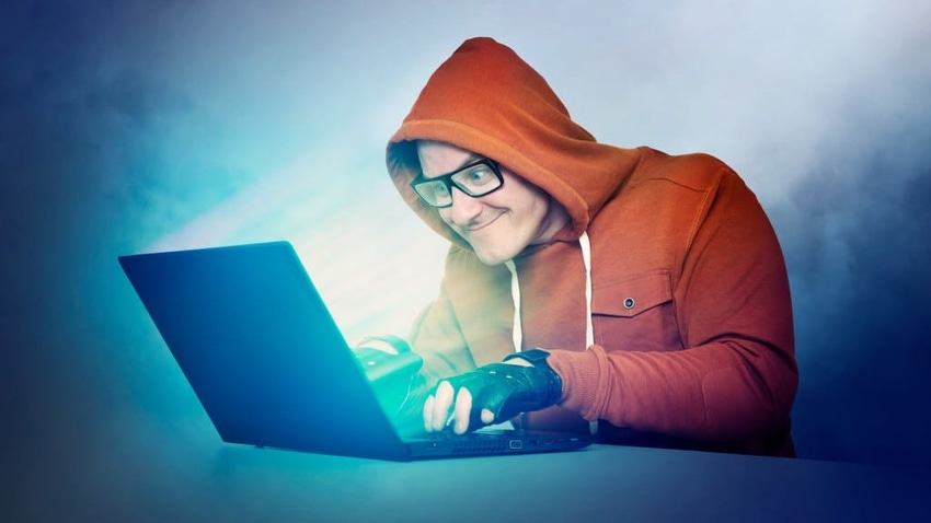 Man in red hoodie in front of a laptop screen looking suspiciously