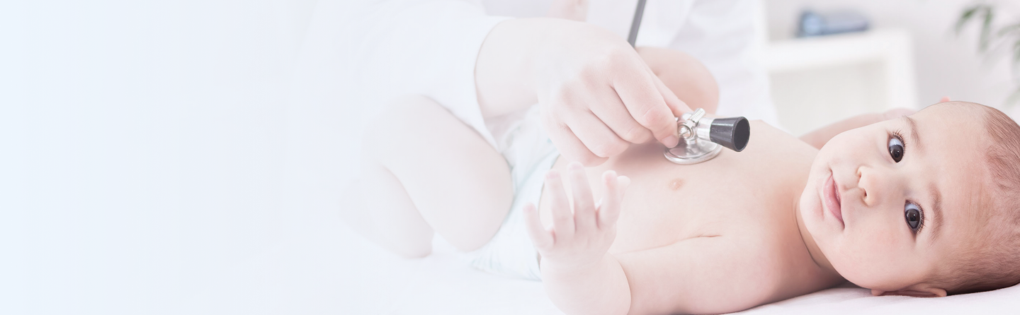 Healthcare professional using stethoscope to examine infant lying on examination table in medical setting