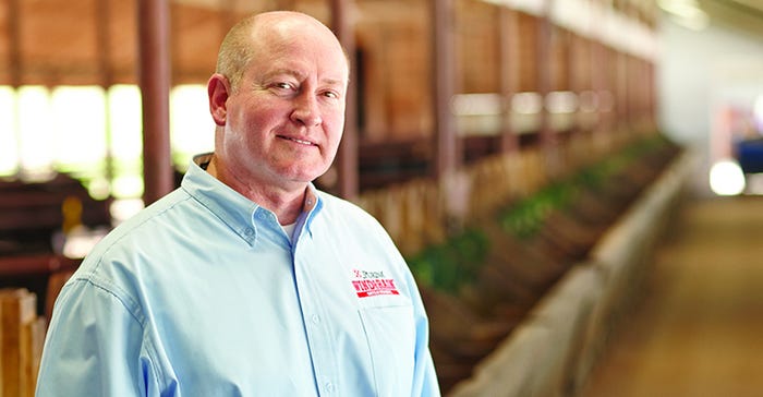 Headshot of Purina’s Dr. Ron Scott standing in the alley of a cattle barn at the Purina Animal Nutrition Center.