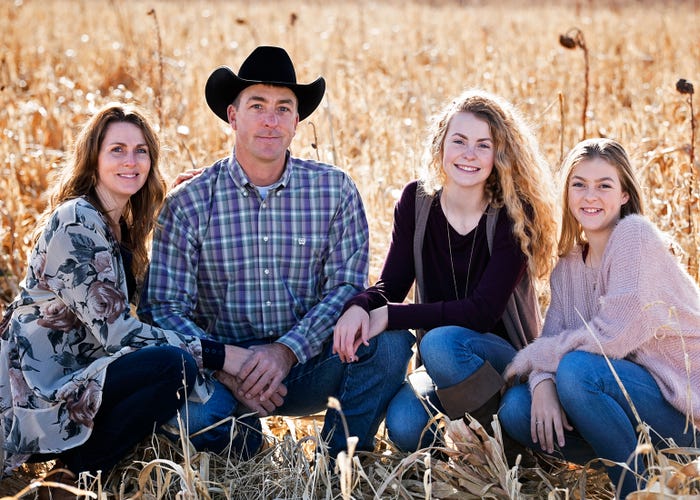 Kristy and Shawn and their daughters, Riley and Ryan, kneel together in a field