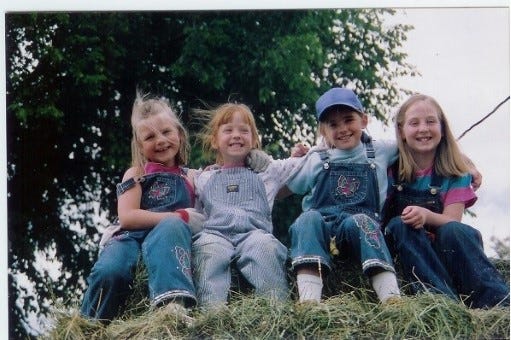 My cousin Mikayla, sister Laura, cousin Kristin, and I baling hay on a warm summer day