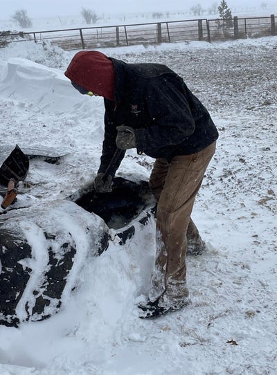 a norby shoveling snow out of water trough