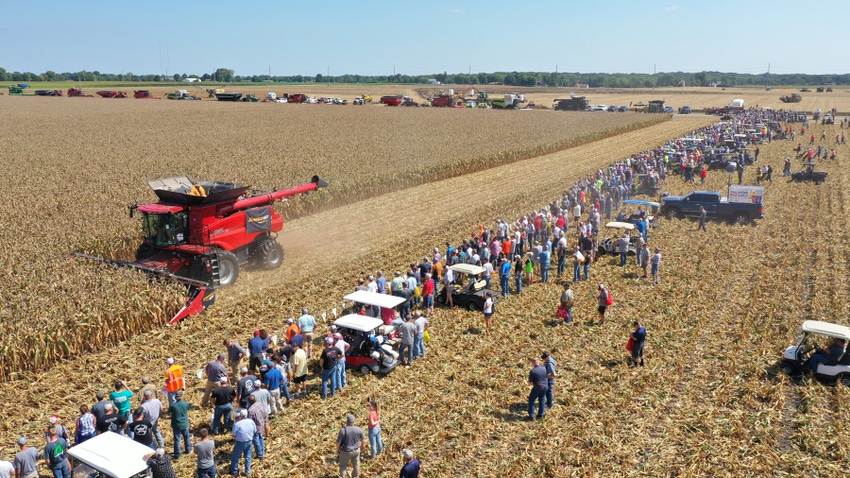 Aerial view of attendees at the Farm Progress Show watching the field demonstration of a combine harvesting corn