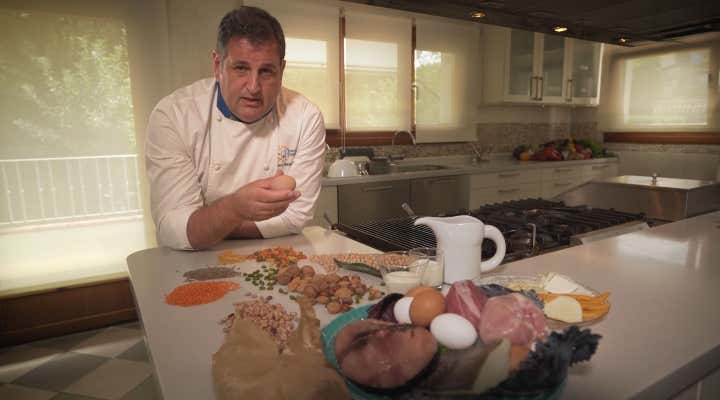 Cocinero explicando que alimentos proporcionan proteinas y carbohidratos.