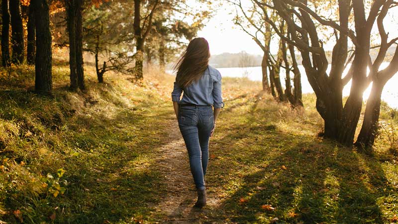 paciente con cáncer de pulmón paseando por un bosque junto a un lago