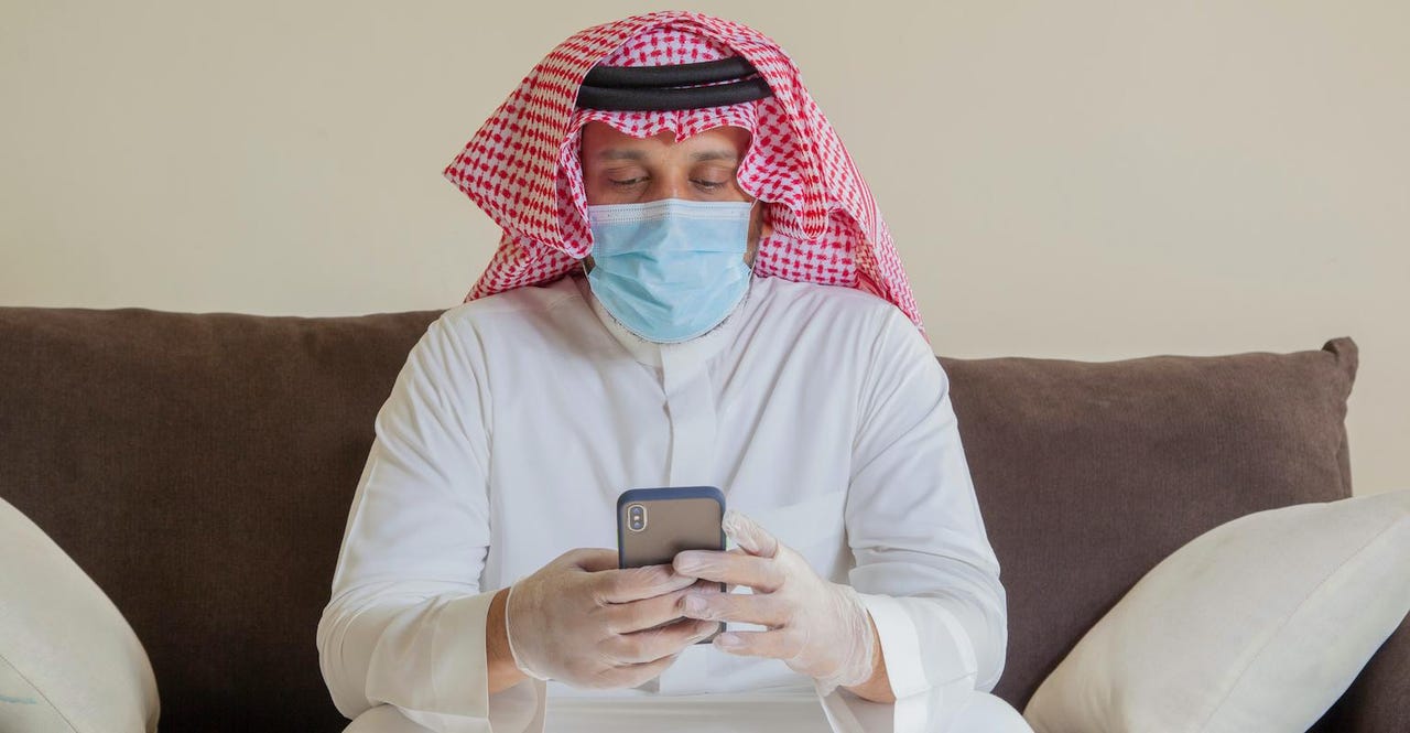 saudi-man-in-mask-and-gloves-looking-at-smartphone.jpg saudi-man-in-mask-and-gloves-looking-at-smartphone.jpg