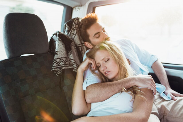 Couple sleeping in the back of the car while holding each other