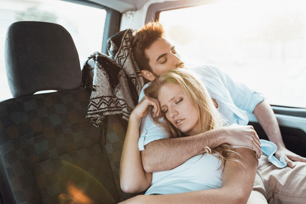 Couple sleeping in the back of the car while holding each other
