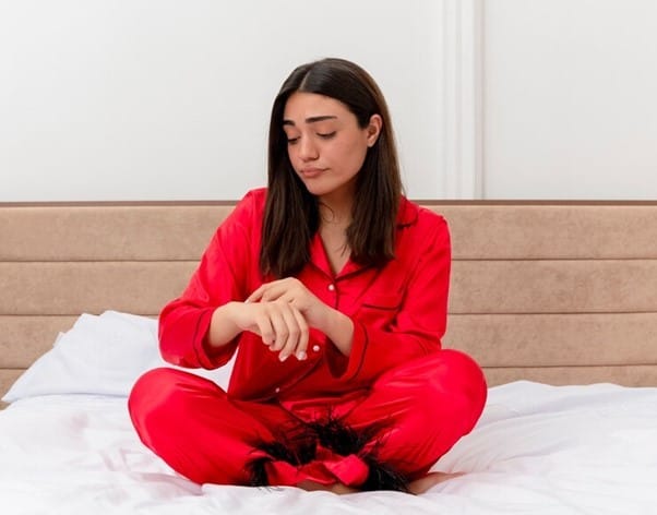 Girl in red pyjama sitting on bed
