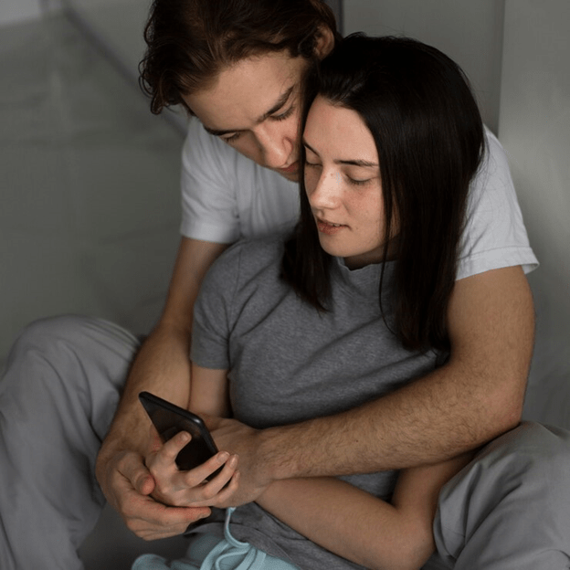 Couple holding each other looking at a phone