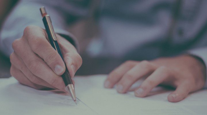 Hand signing a document with a pen