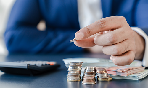 Raisin ES- mano apilando monedas junto a calculadora