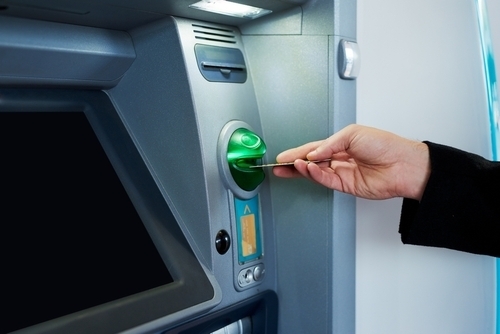 Raisin UK-hand inserting bank card into ATM