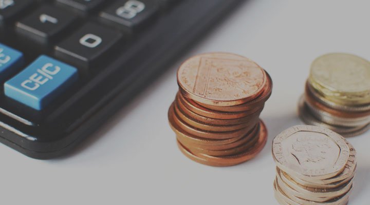 Raisin UK- Calculator beside stacked coins