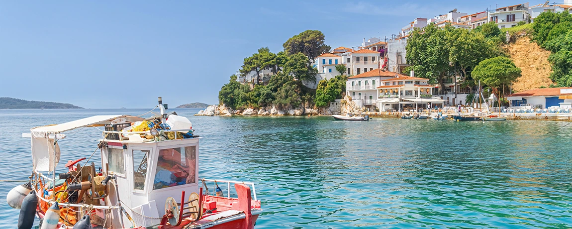 A boat sails at the Old Port in Skiathos, Greece