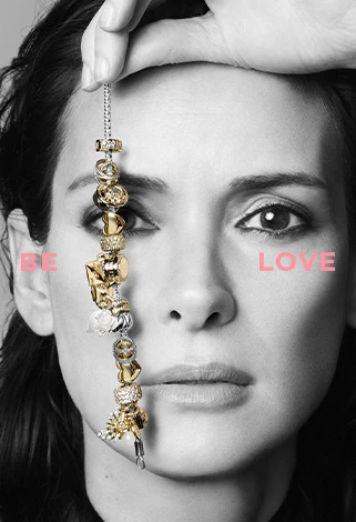 Girl holding up a Pandora charm bracelet, with the words 'Be love' to represent Pandora's message. For mobile users.