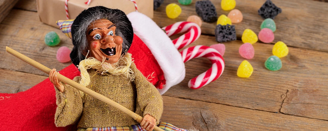 The witch Befana in a red stocking with sweets and coal