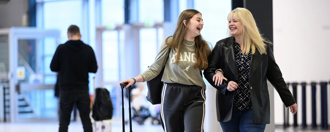two ladies at luton airport smiling.webp