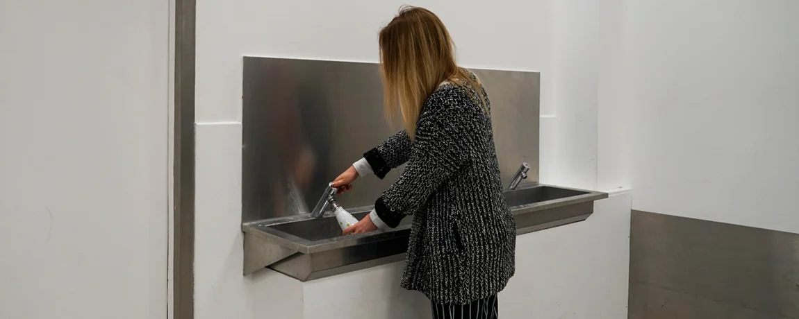 person_filling_water_at_water_fountain.webp
