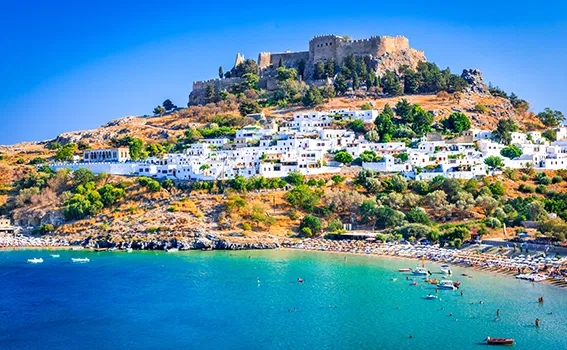Beach with an ancient citadel in the background in Rhodes Greece.