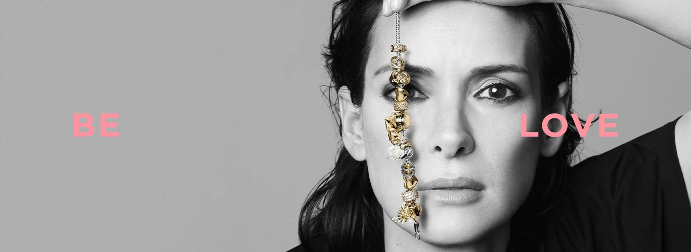 Girl holding up a Pandora charm bracelet, with the words 'Be love' to represent Pandora's message.