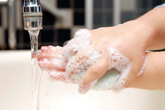 Child using a block of soap to wash hands