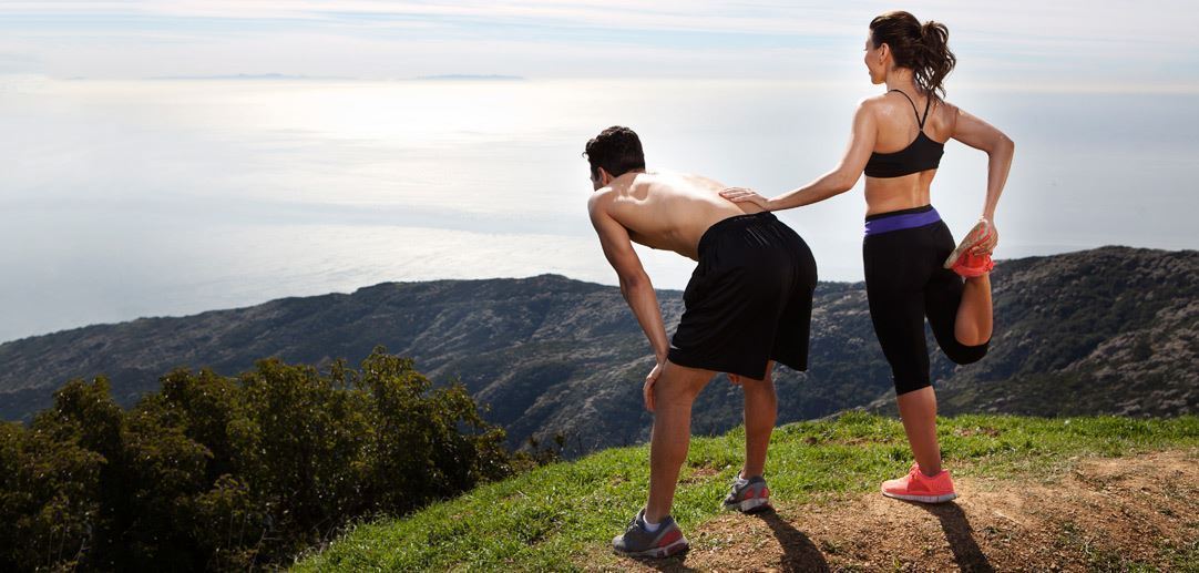 man and woman exercising looking over the sea