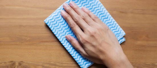 Hand wiping cloth over hard wood surface
