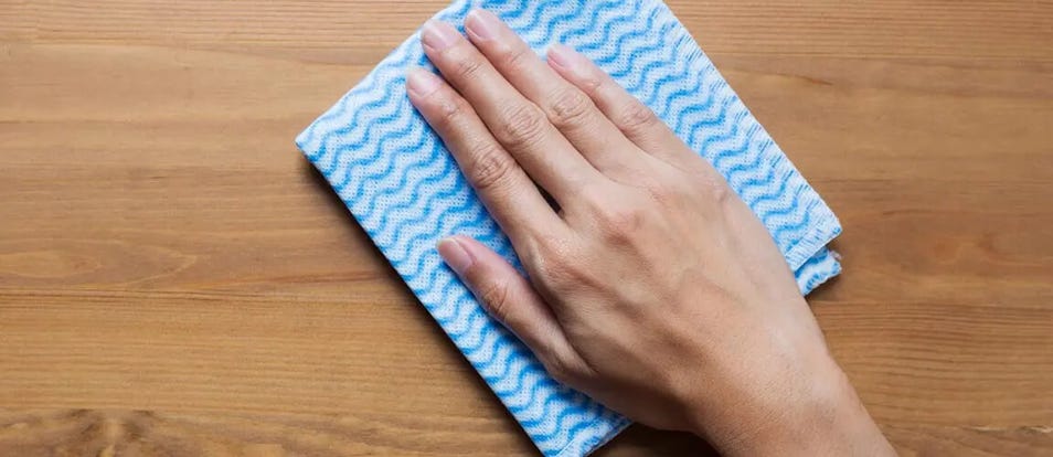 Hand wiping cloth over hard wood surface