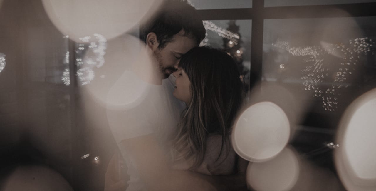 A softly lit couple dance surrounded by soft, glowing lights.