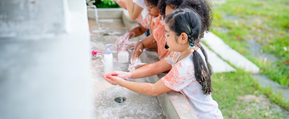 A group of young girls washing their hands in a sink