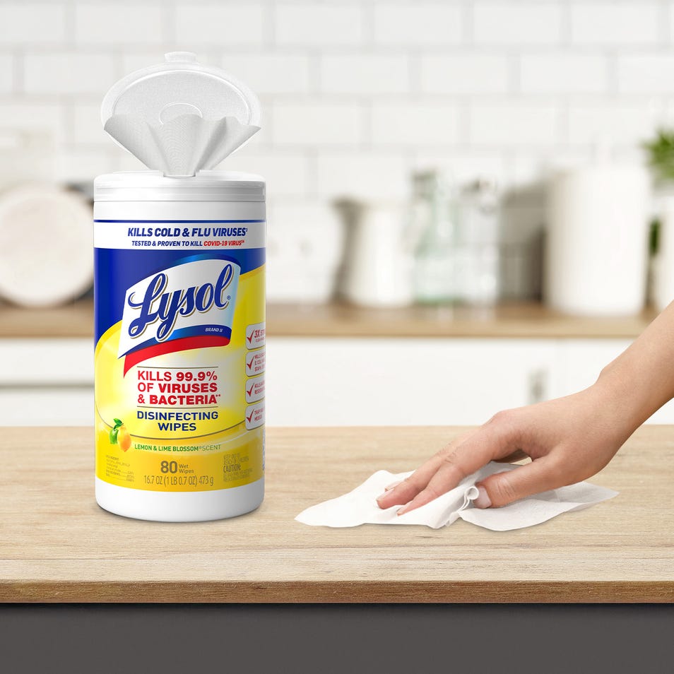 A container of Lysol disinfecting wipes on a kitchen counter with a hand using a wipe.