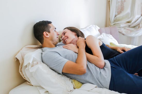 Mujer viendo a su novio muy enamorada acostados en la cama