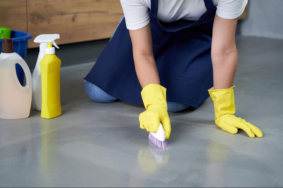 a person wearing gloves cleaning the floor using brush