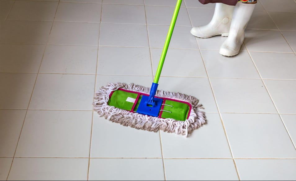 a person wearing white boots cleaning a white tile floor using mop