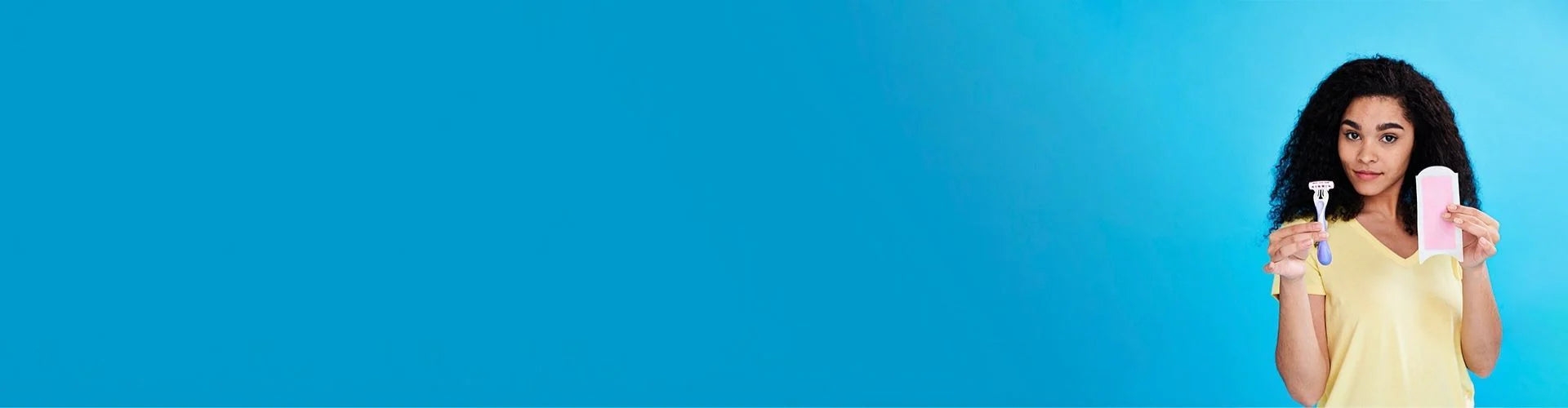 A woman with curly hair smiles warmly in a light yellow top, holding a smartphone against a bright blue background.