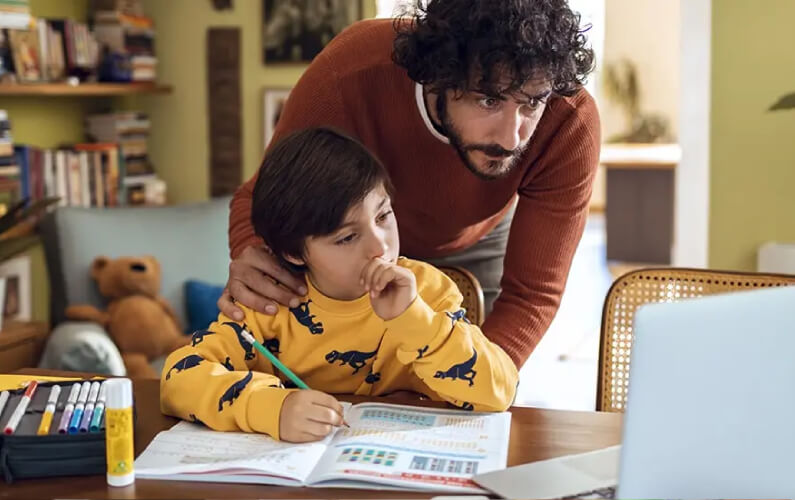 Close up of a father helping his son with schoolwork in their home