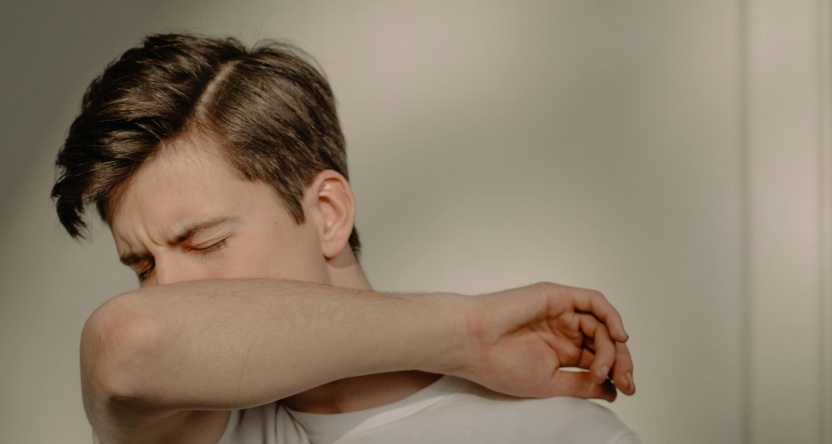 A Man Suffering from Wet Cough covering his mouth with arm