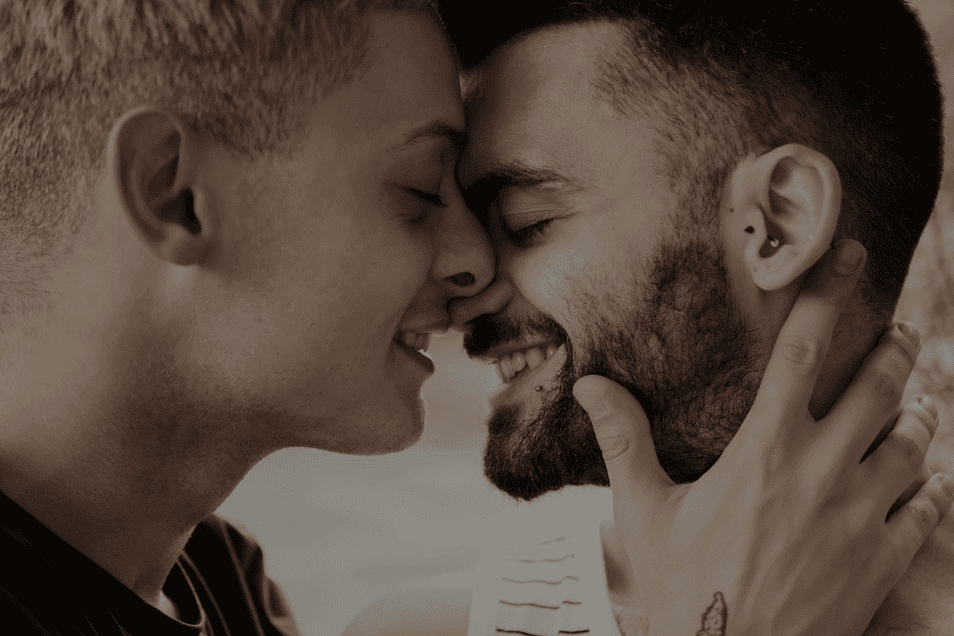 Two men facing each other smiling as if to kiss