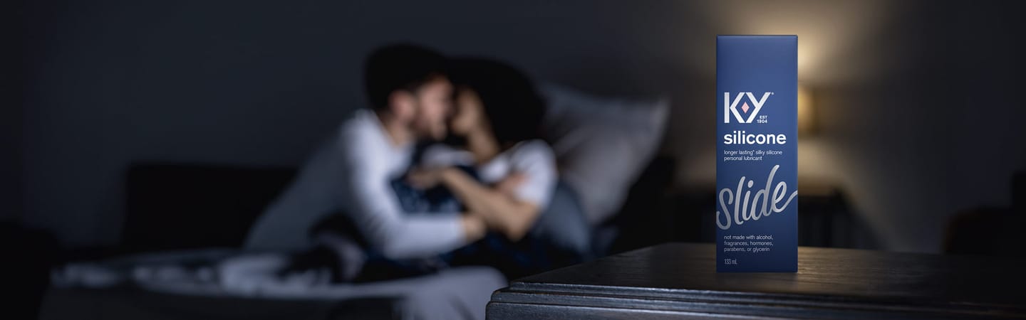 Close-up of K-Y Lubricant - Silicone box in front of a couple embracing in bed.