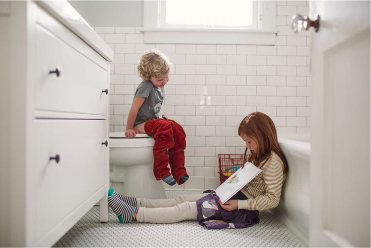 Little girl in pink dress on a toilet