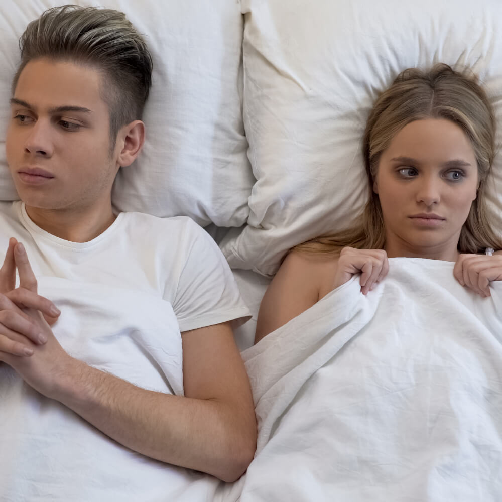 Dos personas acostadas en la cama un poco incomodos