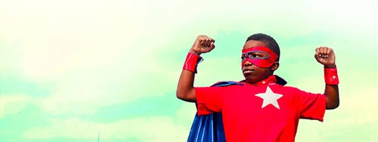 Child posing in superhero costume in front of sky backdrop