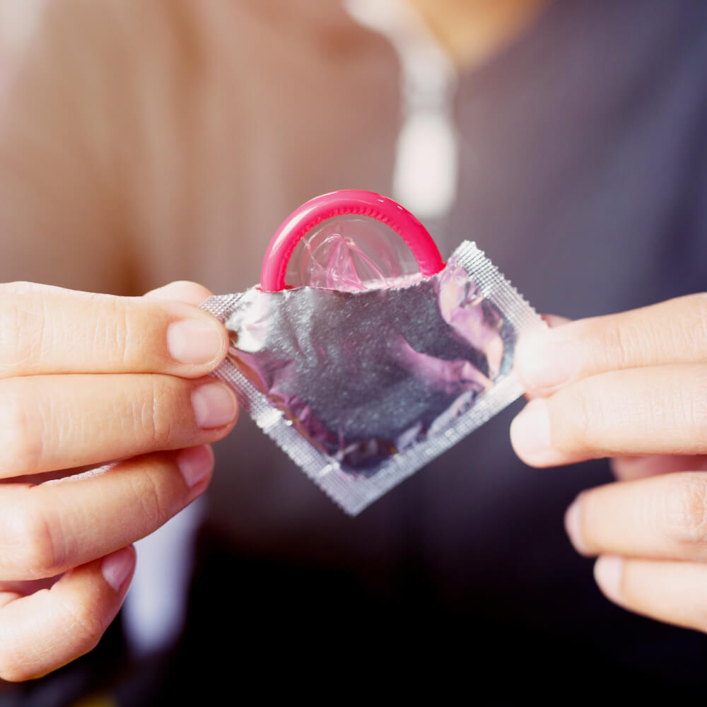 Mujer tomando un condón con la mano