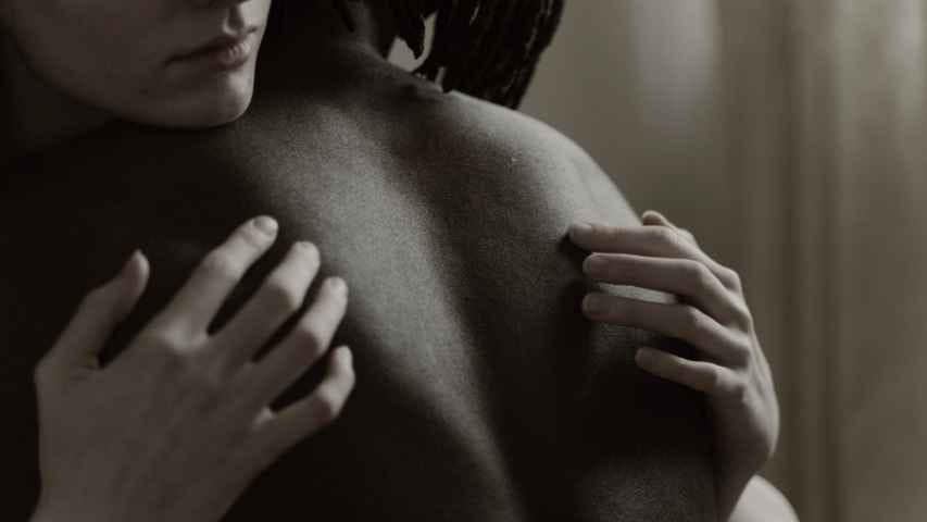 A woman embraces a topless man.