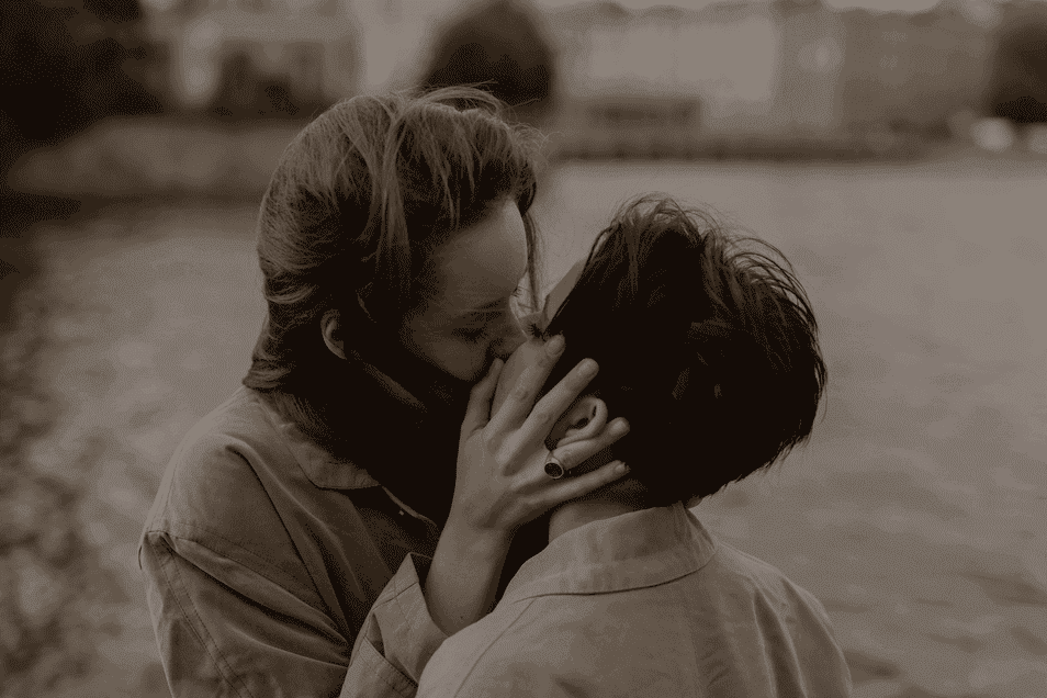 Un couple qui s’embrasse, le vent soufflant dans leurs cheveux.